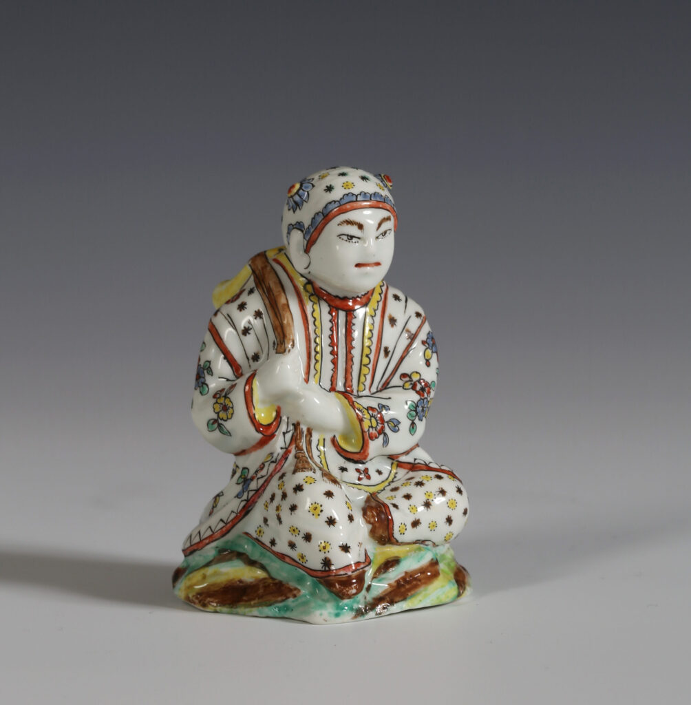 A VILLEROY FIGURE OF A SEATED MAN