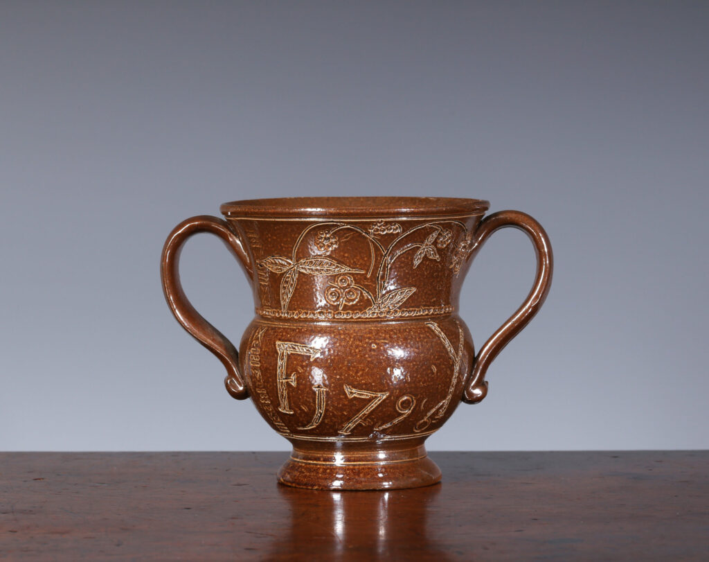 A SMALL SALTGLAZED STONEWARE TWO-HANDLED LOVING CUP