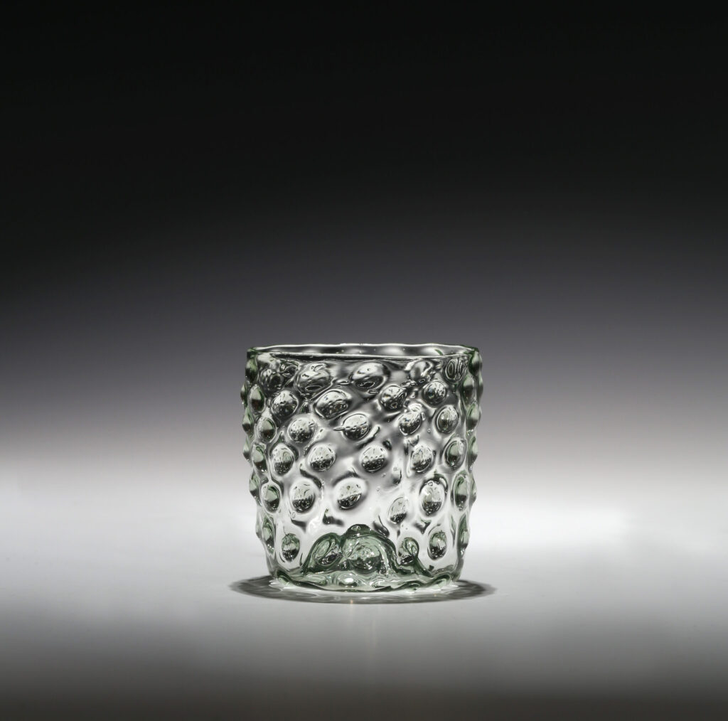 A PALE-GREEN GLASS MOULDED BEAKER WITH RAISED BOSSES