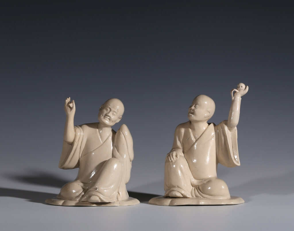 A PAIR OF WHITE SALT-GLAZED STONEWARE FIGURES OF LOHANS