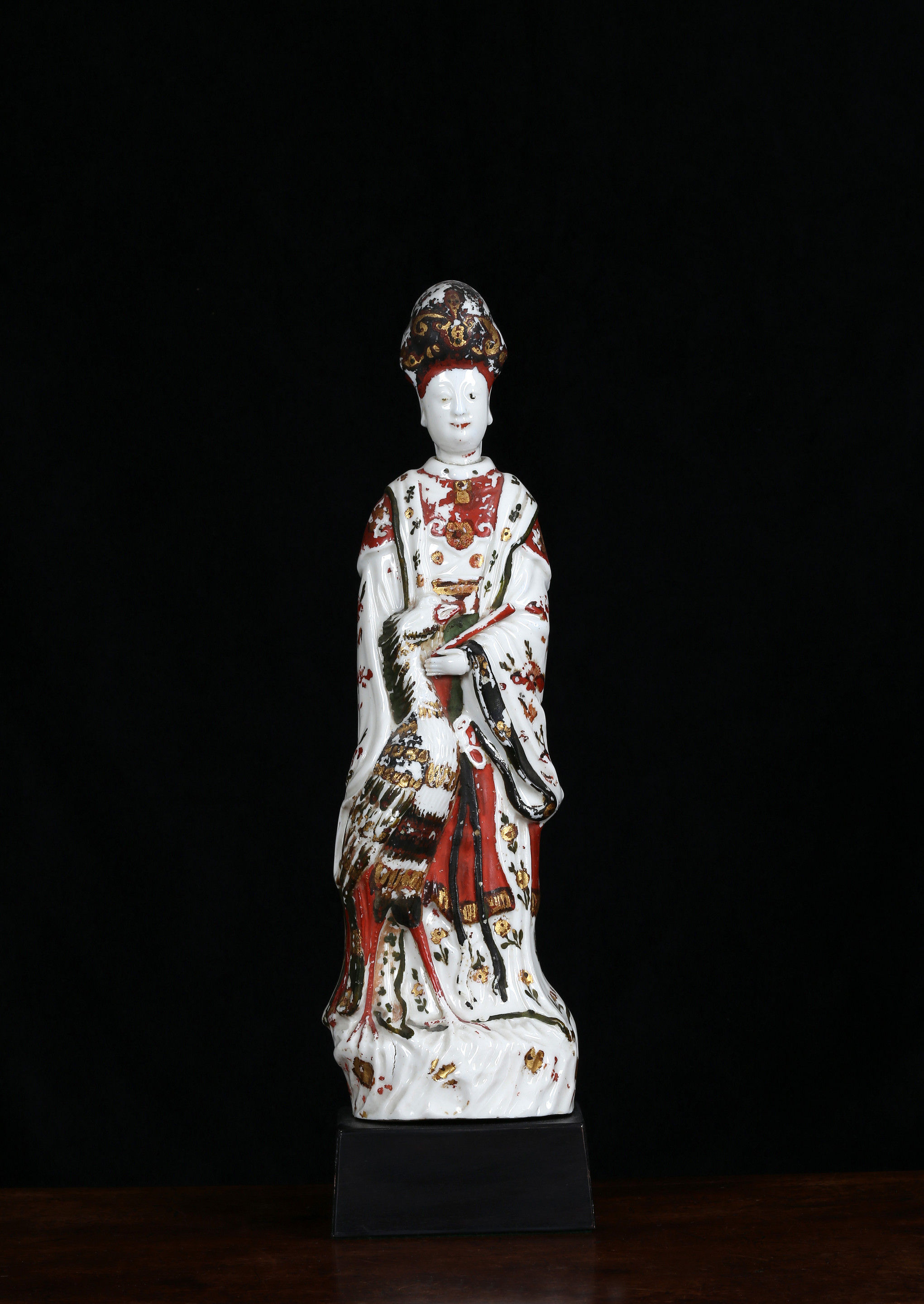 A cold-decorated Dehua figure of Guanyin standing beside a phoenix painted in black gold green and ochre